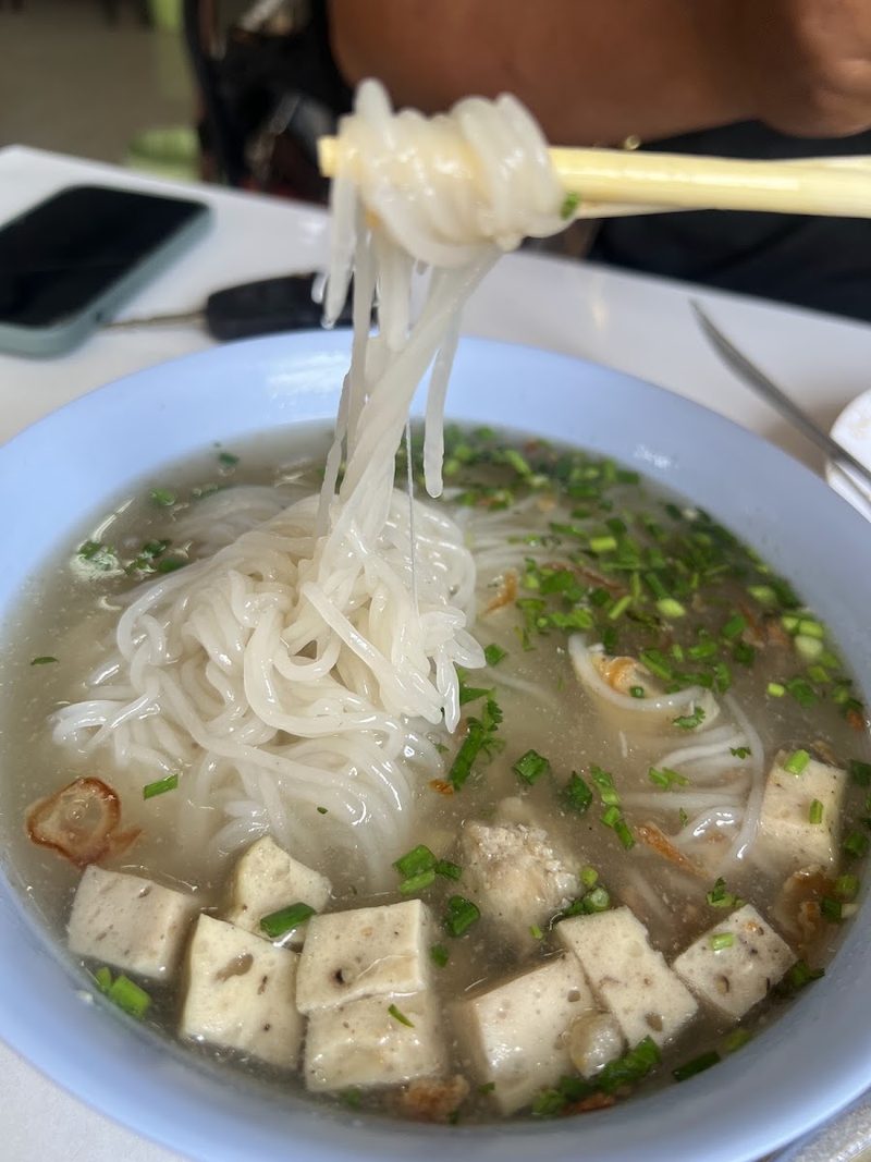 ข้าวเปียกเส้นเหนียวนุ่ม คีบขึ้นจากชามพร้อมหมูยอหั่นเต๋า