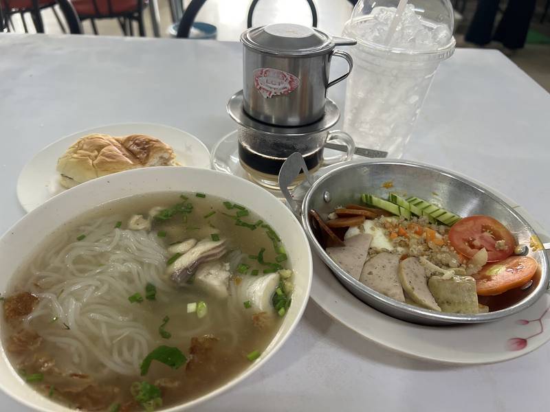ข้าวเปียกเส้นชามใหญ่ วางคู่ไข่กระทะ ขนมปัง และกาแฟดริปแบบเวียดนาม