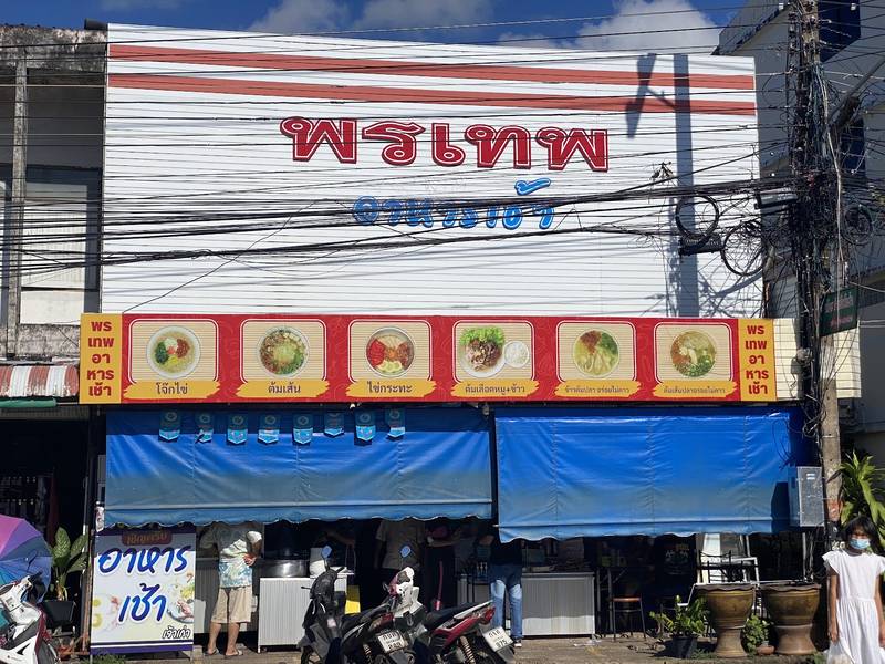หน้าร้านพรเทพอาหารเช้า ป้ายตัวอักษรแดง แถบรูปเมนู และกันสาดสีฟ้า
